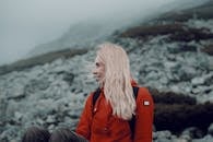 Woman in Red Jacket Sitting on Rock