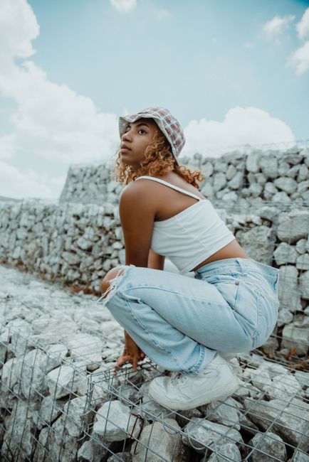 Young woman in casual clothing poses creatively outdoors on stone steps.