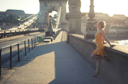 Woman in Dress Standing on Sidewalk