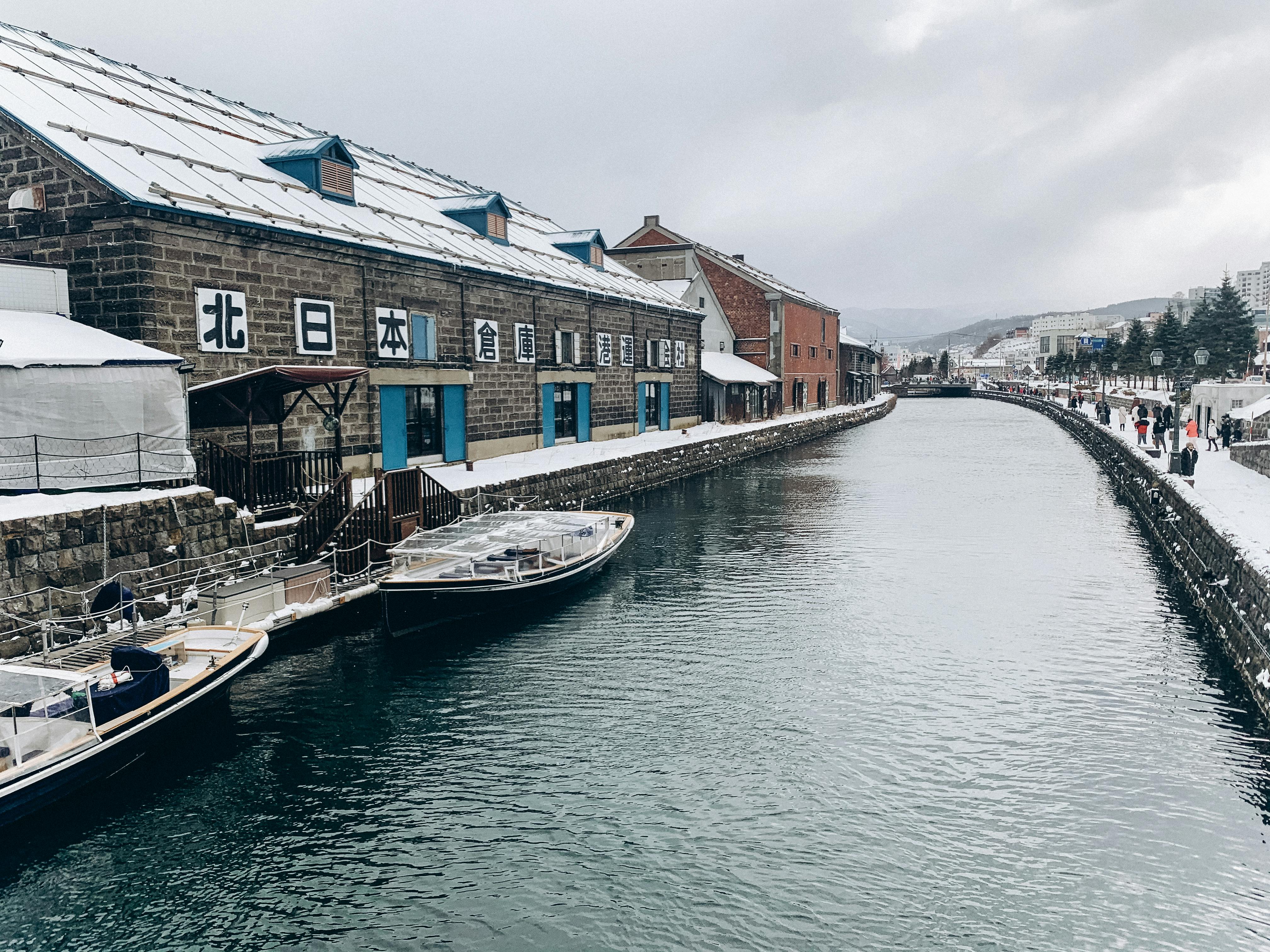 Otaru Canal at twilight with historic stone warehouses glowing under warm gas lamps reflecting on dark water