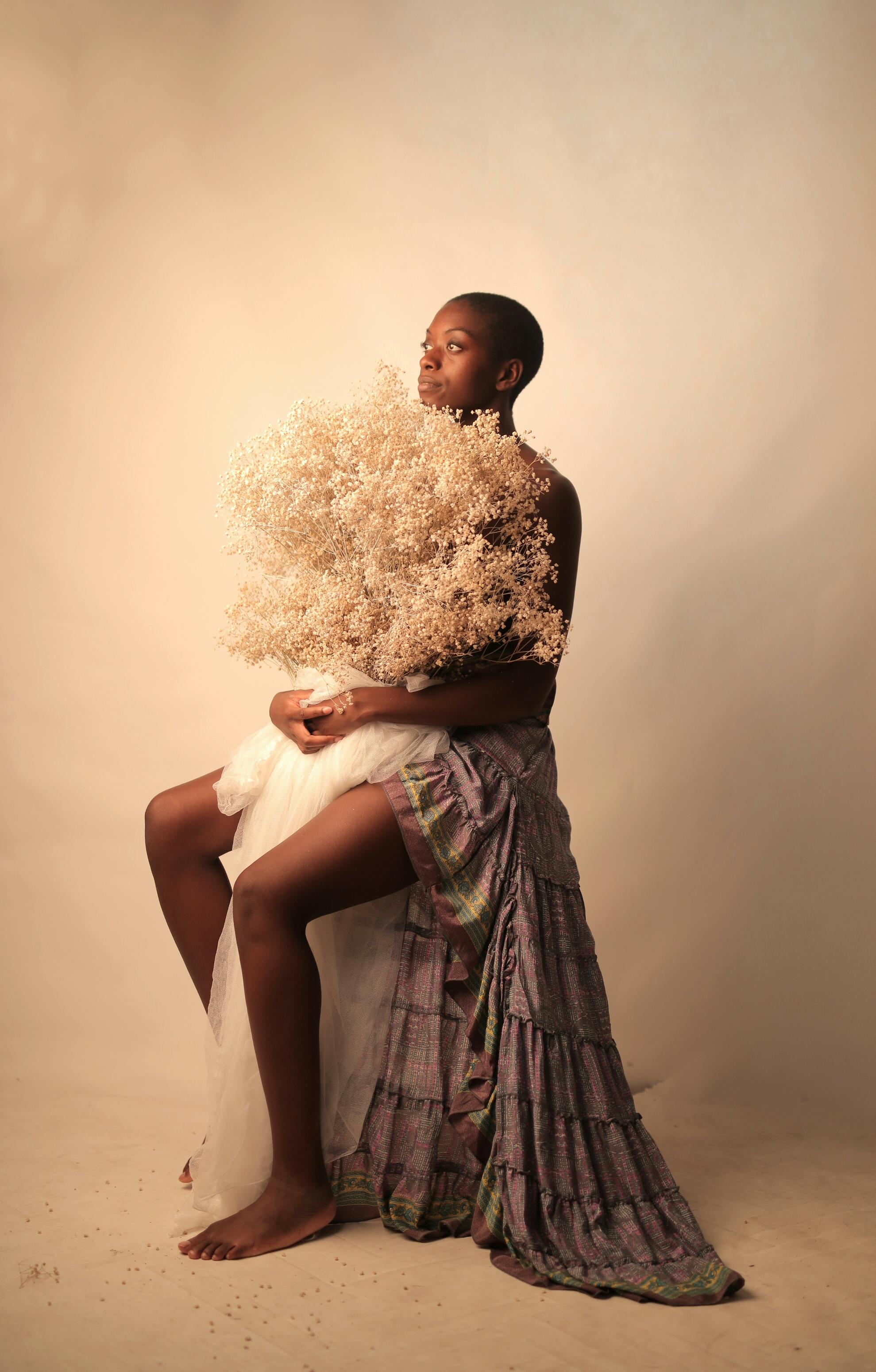 Stunning studio portrait of a woman holding white flowers, styled with a draped skirt.