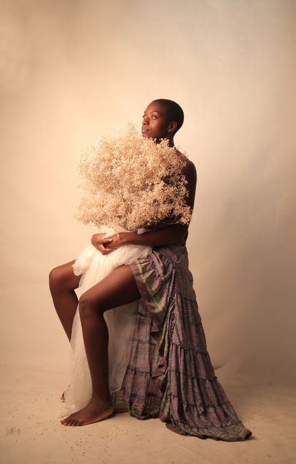 Stunning studio portrait of a woman holding white flowers, styled with a draped skirt.