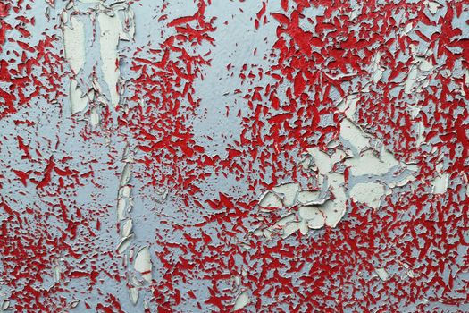 Close-up of a peeling red and white wall texture showing cracked and rough patterns.