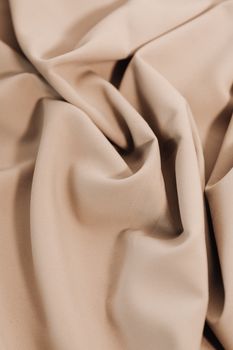 A detailed close-up shot showcasing smooth beige fabric with elegant folds and texture.