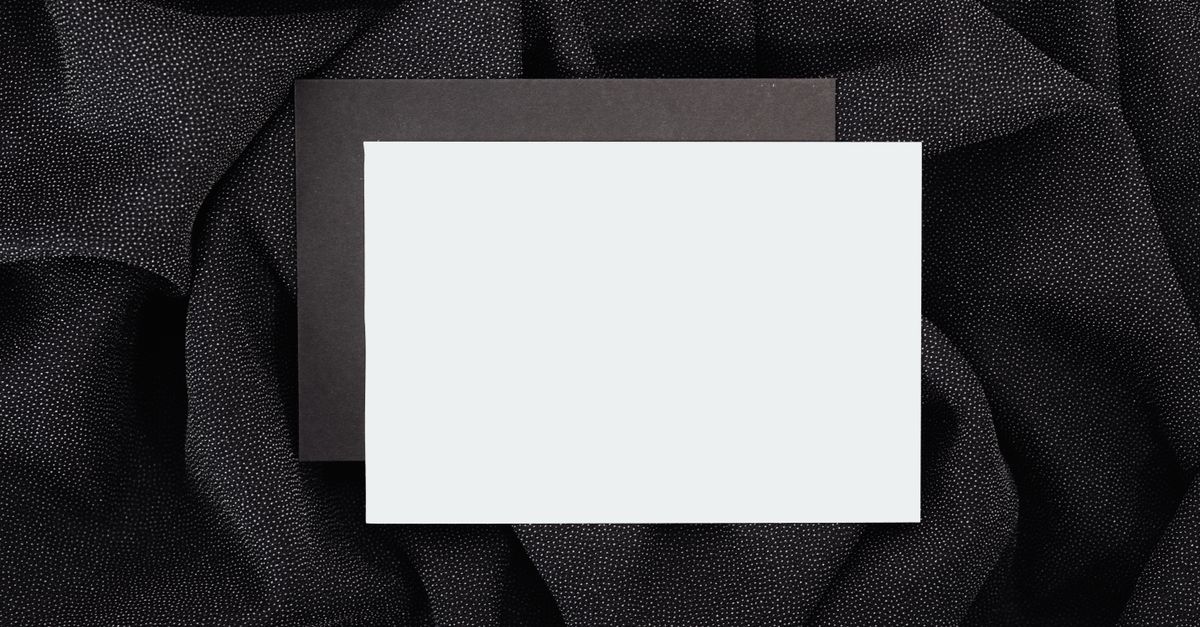Blank black and white card on textured black cloth, ideal for designs.