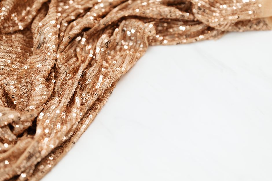 Close-up of beige fabric adorned with shiny sequins for a glamorous look.
