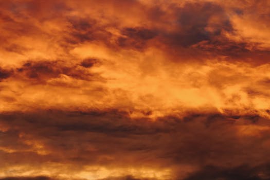 A striking display of vivid orange clouds during a sunset, creating a dramatic sky scene.