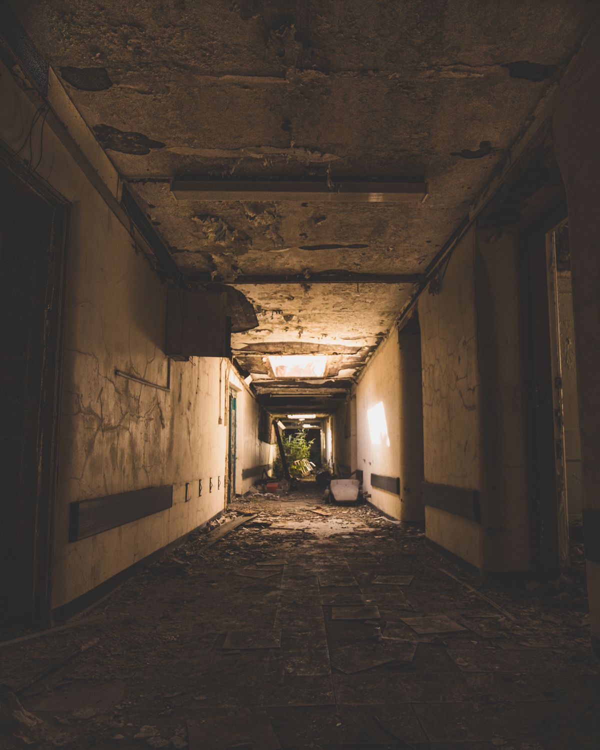 Dimly lit, decaying hospital corridor with peeling walls and archways, illustrative photo