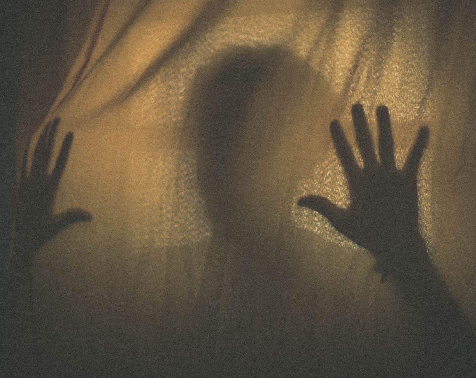 A solitary figure standing in deep shadow, lit by a thin red glow