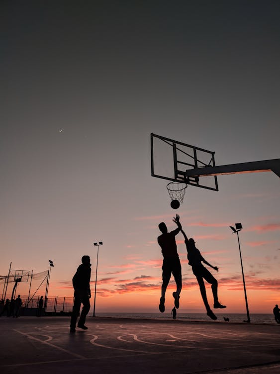 Silhueta De Pessoas Jogando Basquete Durante O Pôr Do Sol · Foto