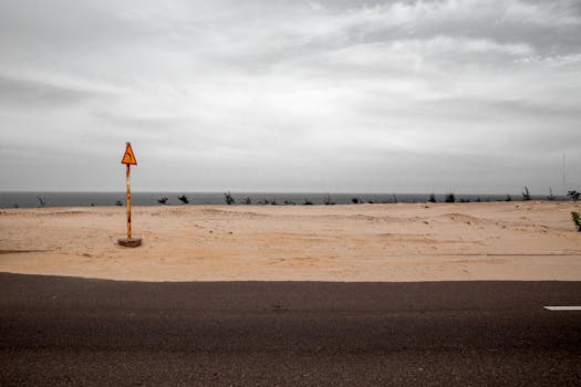 Dramatic seascape with a lone warning sign on a sandy beach near Phan Thiet, Vietnam.
