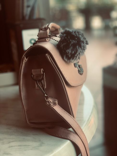 Stylish brown leather shoulder bag with fur accent on table in soft lighting. - Effective Cleaning Techniques for Handbags