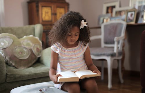 Cute Girl With a Flower on Her Hair Reading a Book