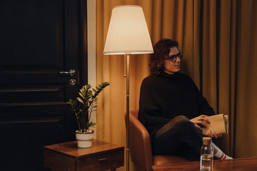 Woman in Black Long Sleeve Shirt Sitting on Brown Armchair