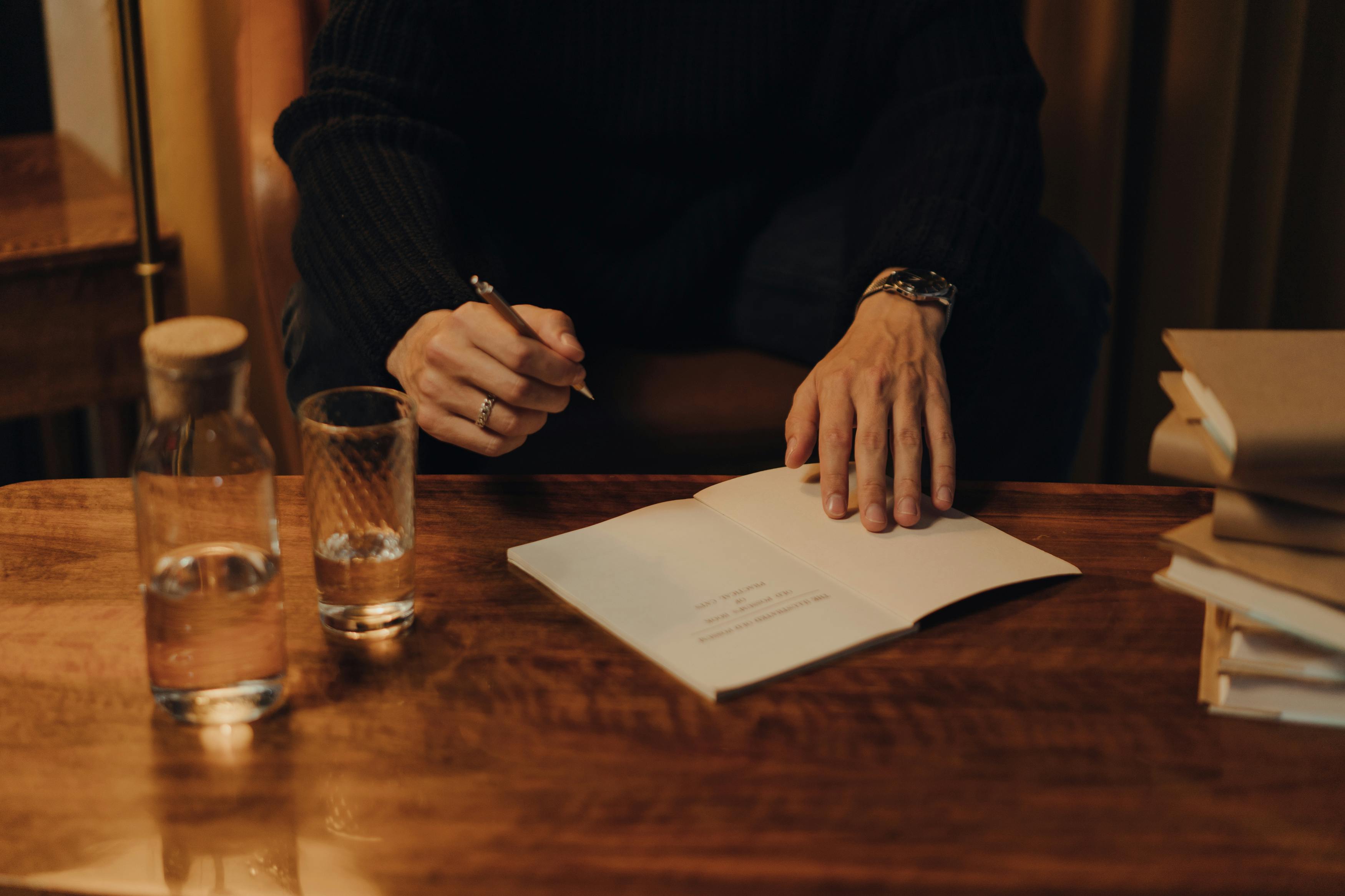 Man signing books during an intimate creative event in a cozy indoor setting.