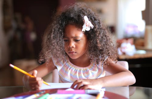 Girl With a Flower on Her Hair Doing Her Homework