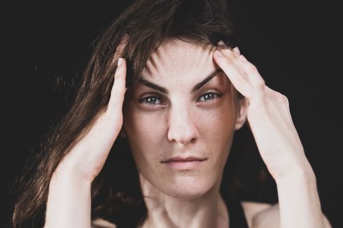 Free Close-up portrait of a woman holding her head, expressing stress or concentration. Stock Photo
