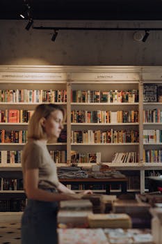 一位年轻女子在温暖舒适的书店里，周围都是文学作品，正静静地看着书