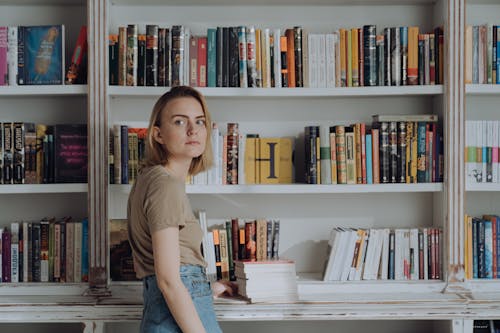 Woman in Brown Crew Neck T-shirt Sitting on White Book