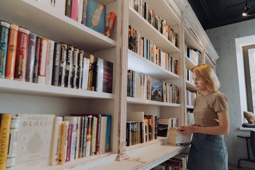 Woman in Gray Shirt Standing in Front of Books