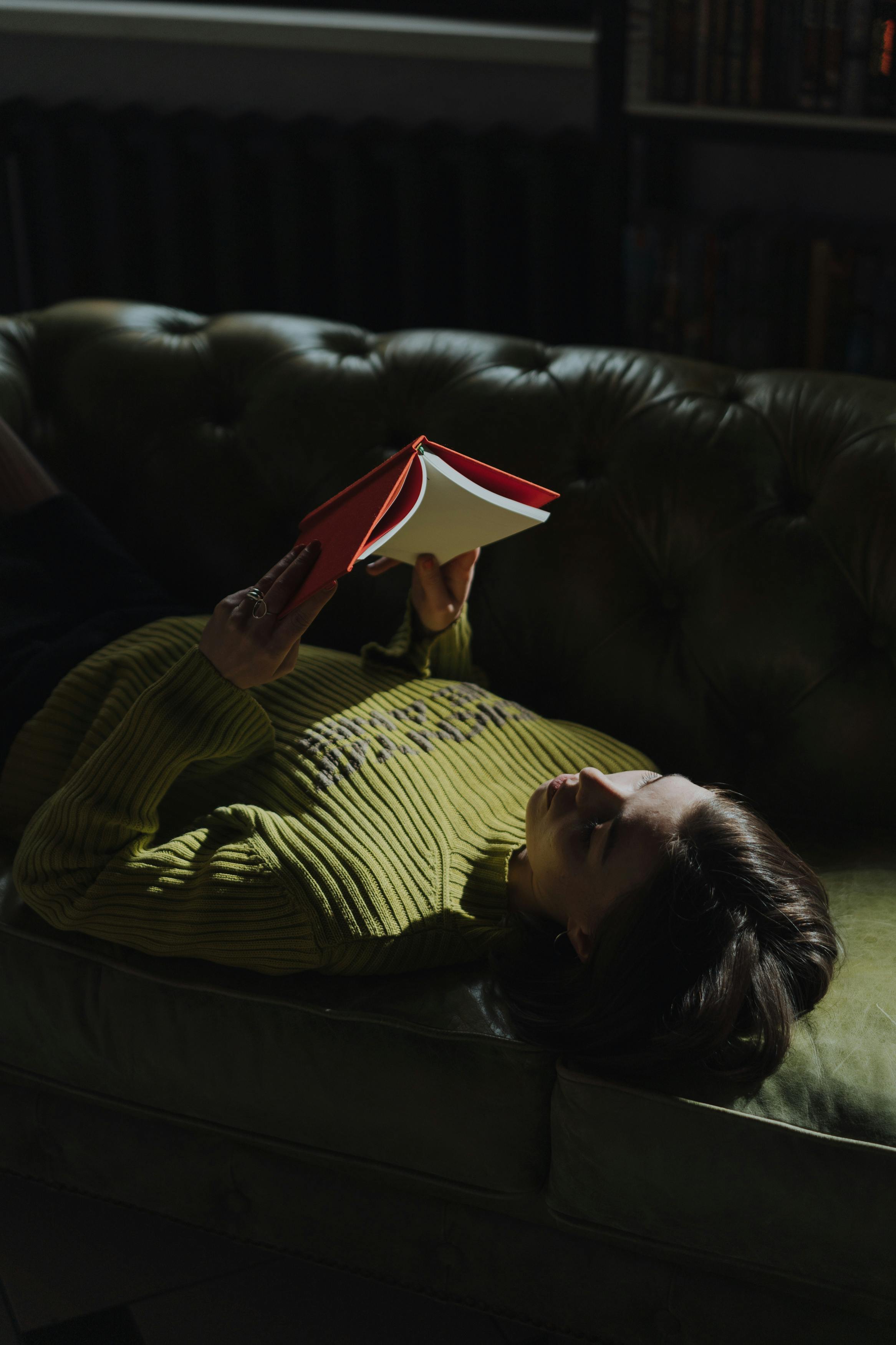 woman in yellow and black striped long sleeve shirt lying on black leather couch