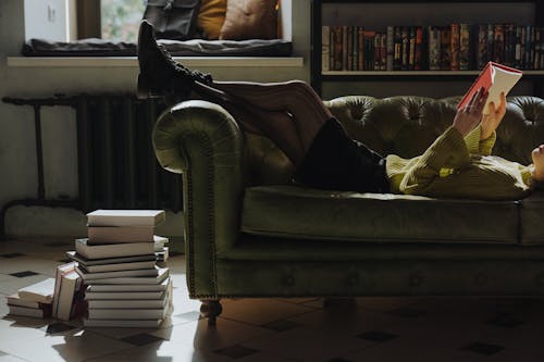 Человек, лежащий на диване и читающий книгу