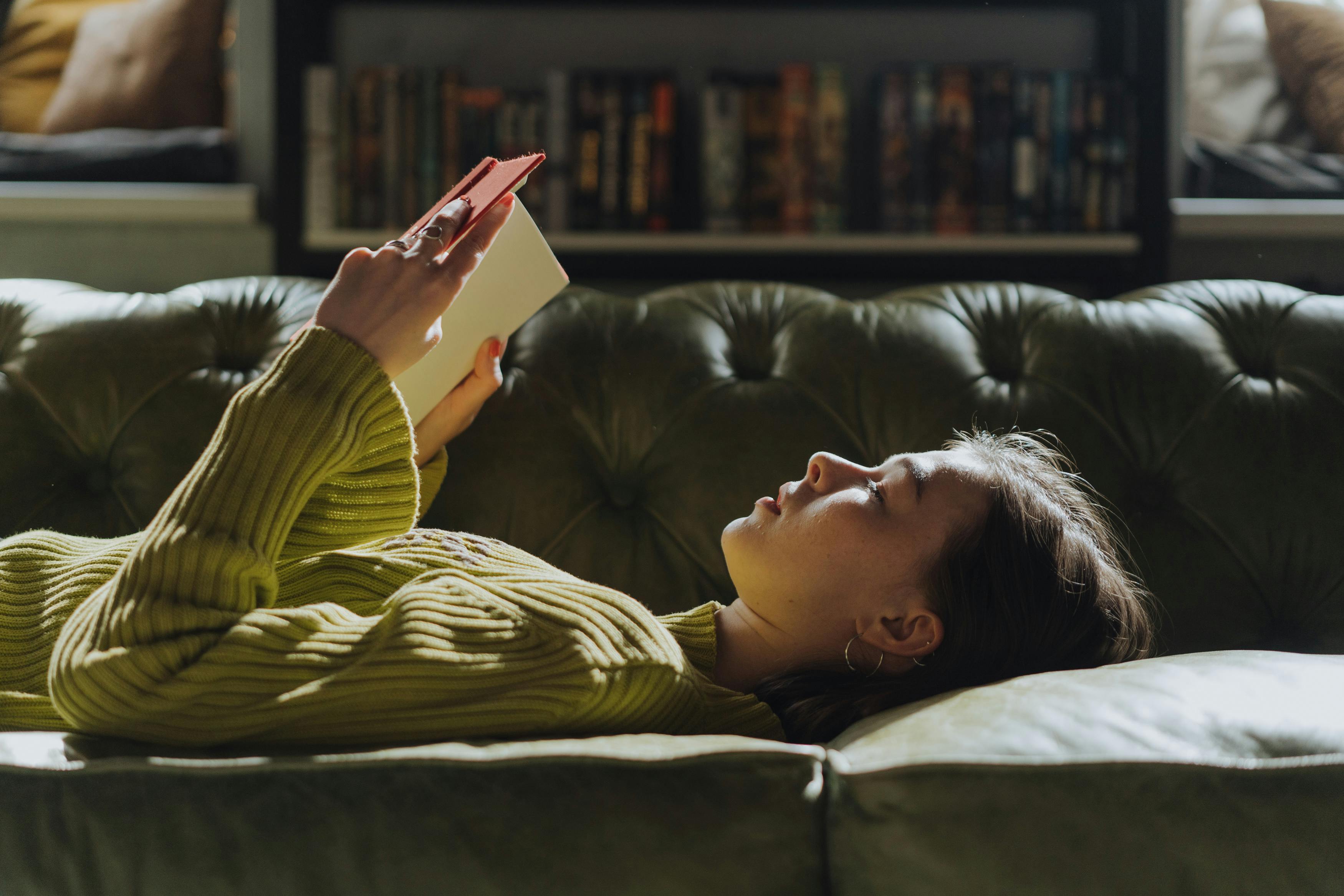 Woman reading book on couch.