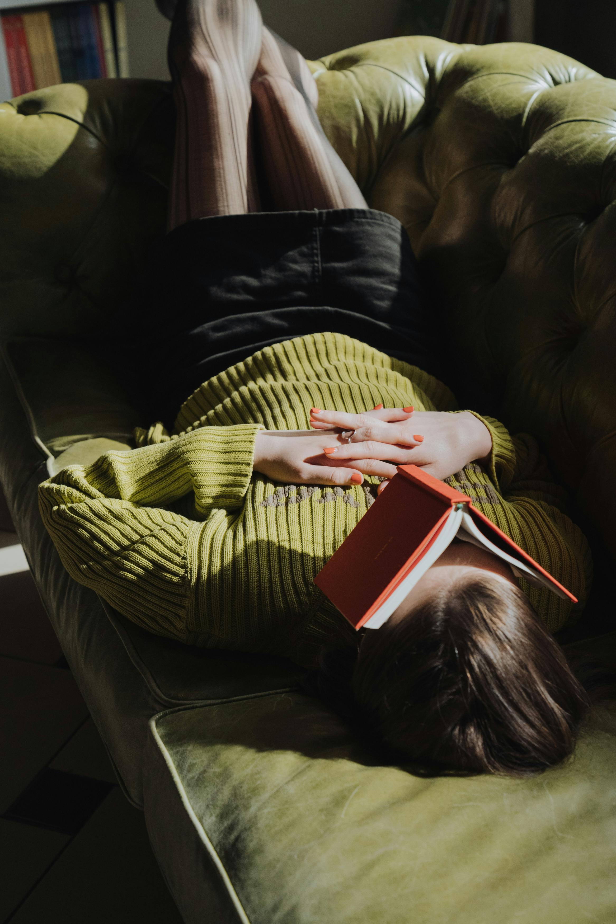 woman in green sweater holding red book