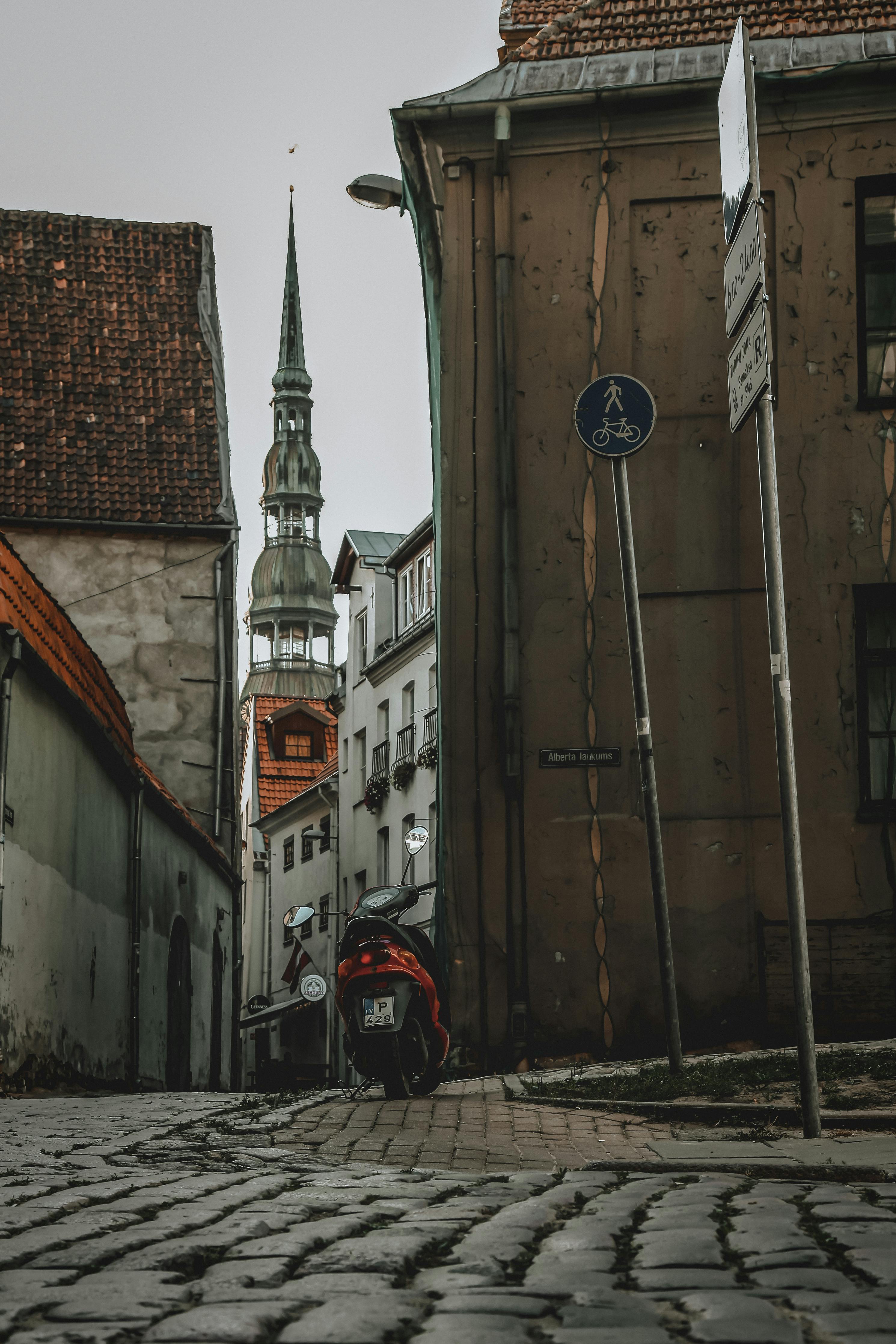 Narrow pedestrian alley running through historic buildings towards old church in Riga Latvia on overcast day