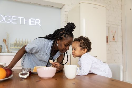 Free A mother and child share a heartwarming moment in their kitchen, symbolizing love and family. Stock Photo