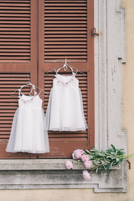 Charming white dresses on hangers with pink flowers on a rustic window.