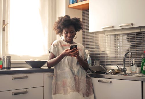 Woman with Cellphone in Kitchen