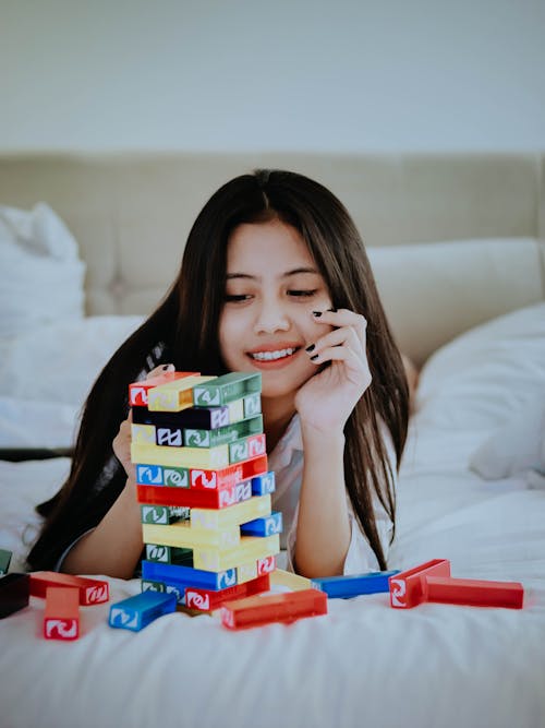 Girl Lying on the Bed and Playing with Blocks 