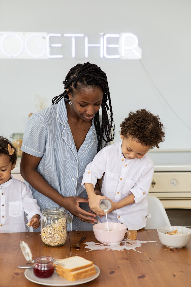 Mother And Child Pouring Milk To Bowl