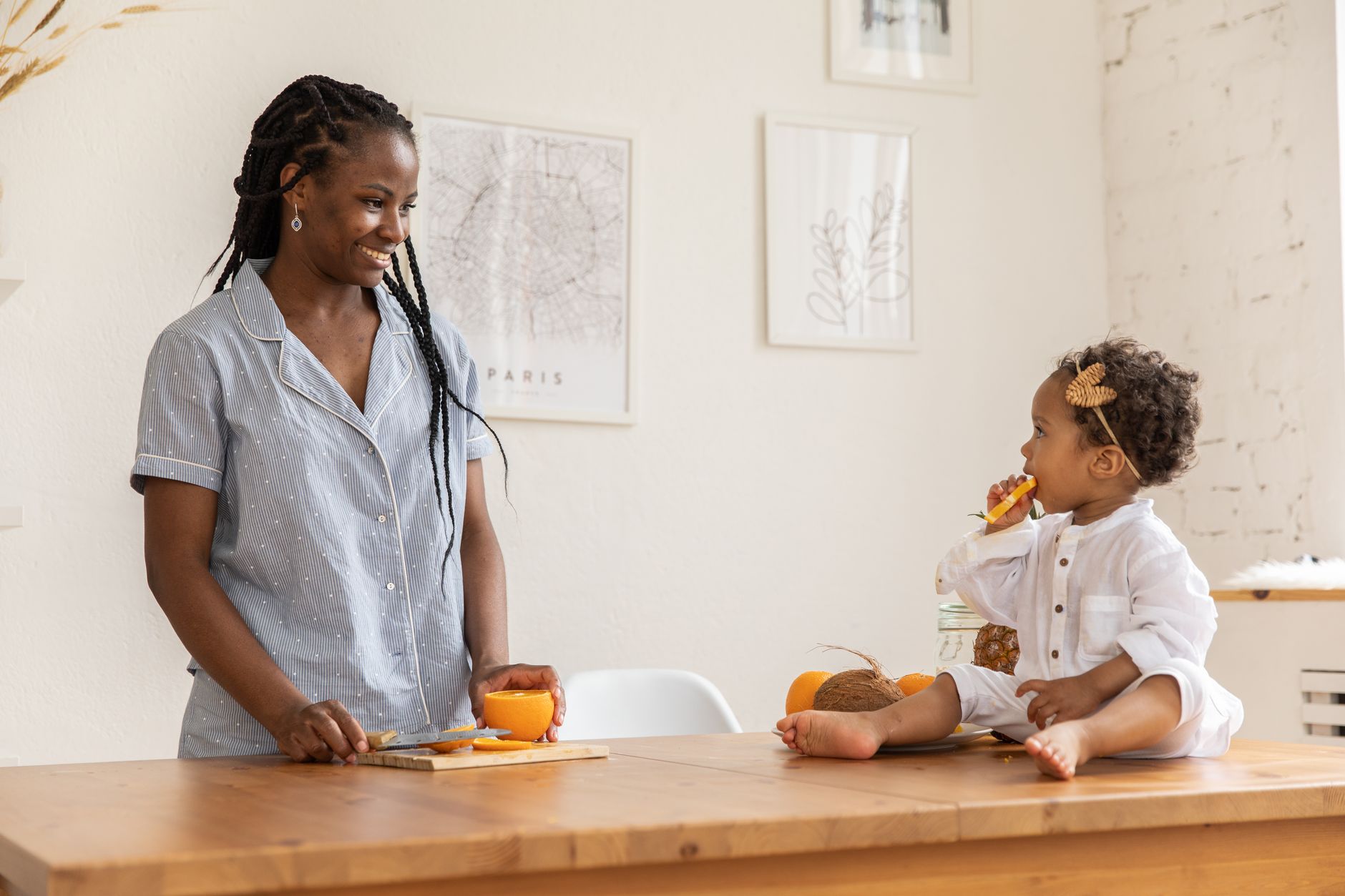 A mother and child enjoying fresh oranges together in a cozy modern kitchen.
