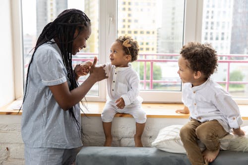 Free Mother Playing With Her Children Sitting on Windowsill Stock Photo