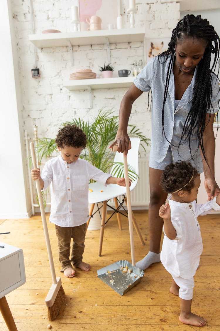 Woman Cleaning Room With Children 