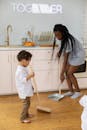 Woman in White Button Up Shirt Holding Broom