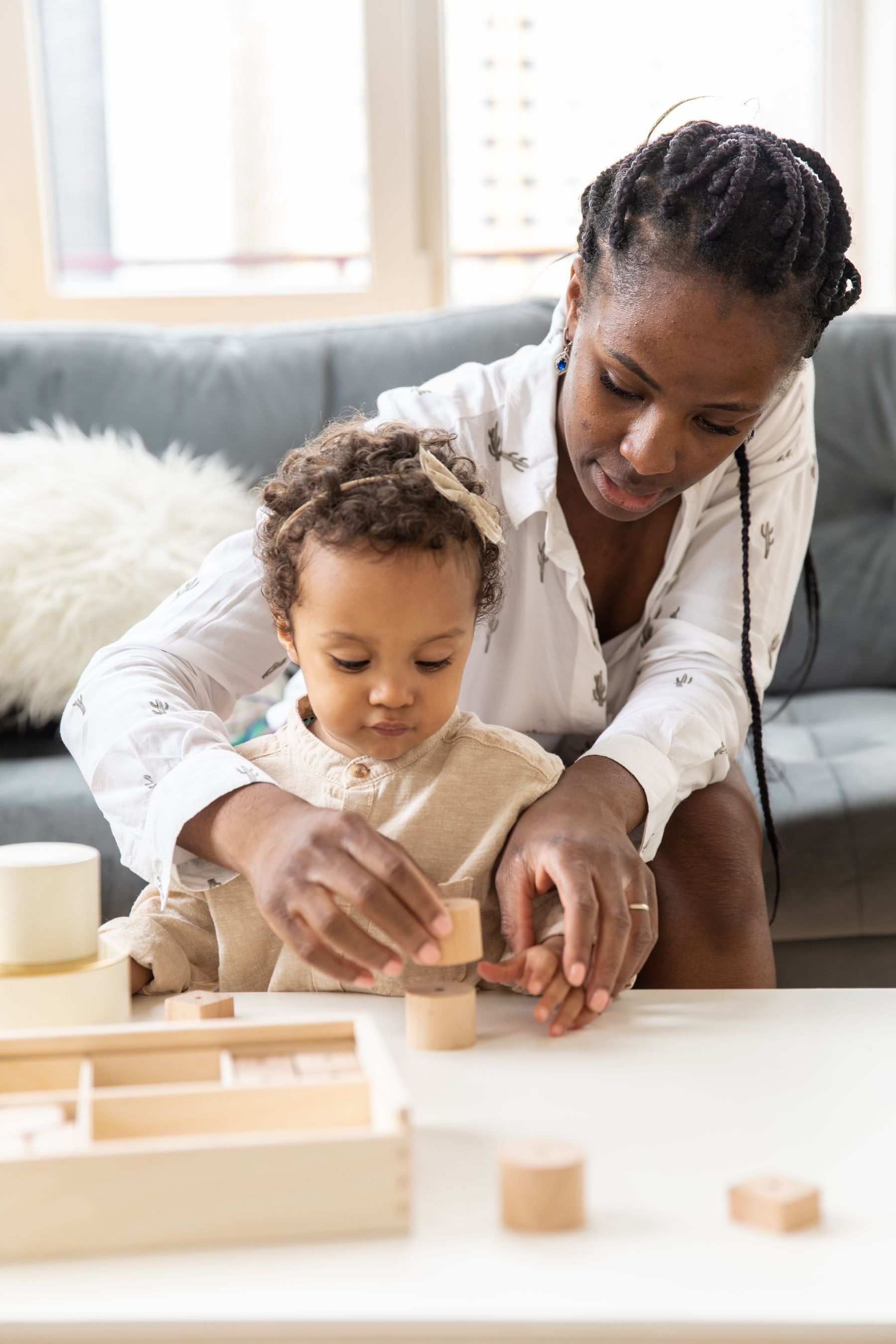 A mother and child sitting together at home while building and arranging wooden learning blocks