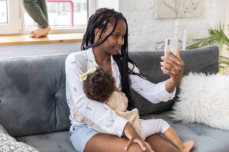 Woman Holding Her Child In Her Arms And Talking On A Video Call