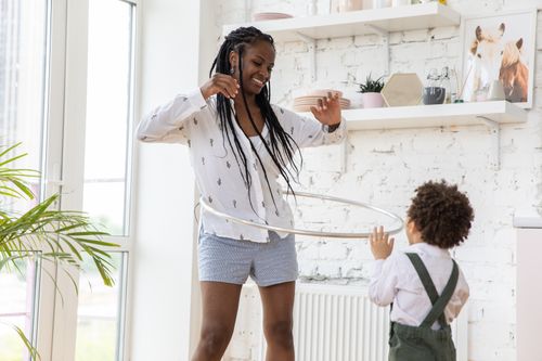 Free A joyful moment of a mother and child playing with a hula hoop in a bright living room. Stock Photo