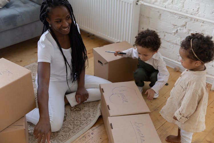 Family Labeling Cardboard Boxes Sitting On Floor