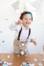 一个快乐的孩子戴着派对帽子，在室内用五彩纸屑庆祝