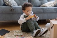 Little Boy Sitting on Ground Drinking Juice