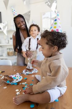 Happy family enjoying a fun birthday celebration with cake and party hats indoors.