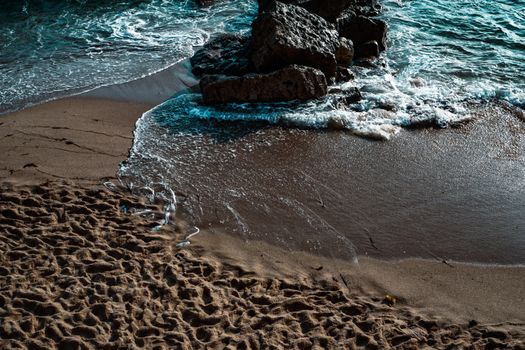 Peaceful beach in Ericeira, Portugal, with waves crashing on the rocks and golden sand.