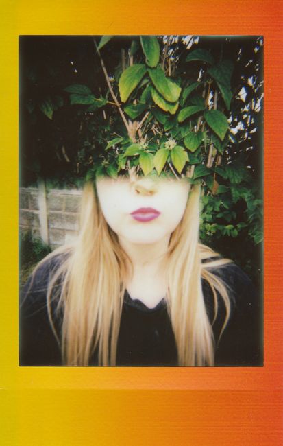 Unique portrait of a woman with foliage using analogue photography style.
