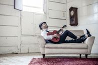 Woman in Black Long Sleeve Shirt and Blue Denim Jeans Sitting on Gray Sofa