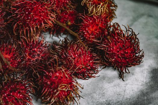 Vibrant and exotic rambutan fruit displayed on a textured gray surface.