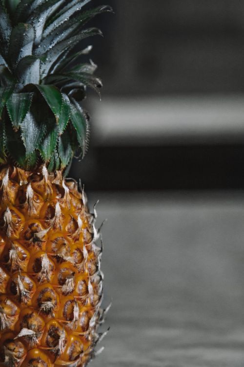 Free Detailed close-up of a ripe pineapple with textured skin and green leaves. Stock Photo